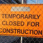 Panneau orange sur clôture indique fermeture temporaire pour travaux