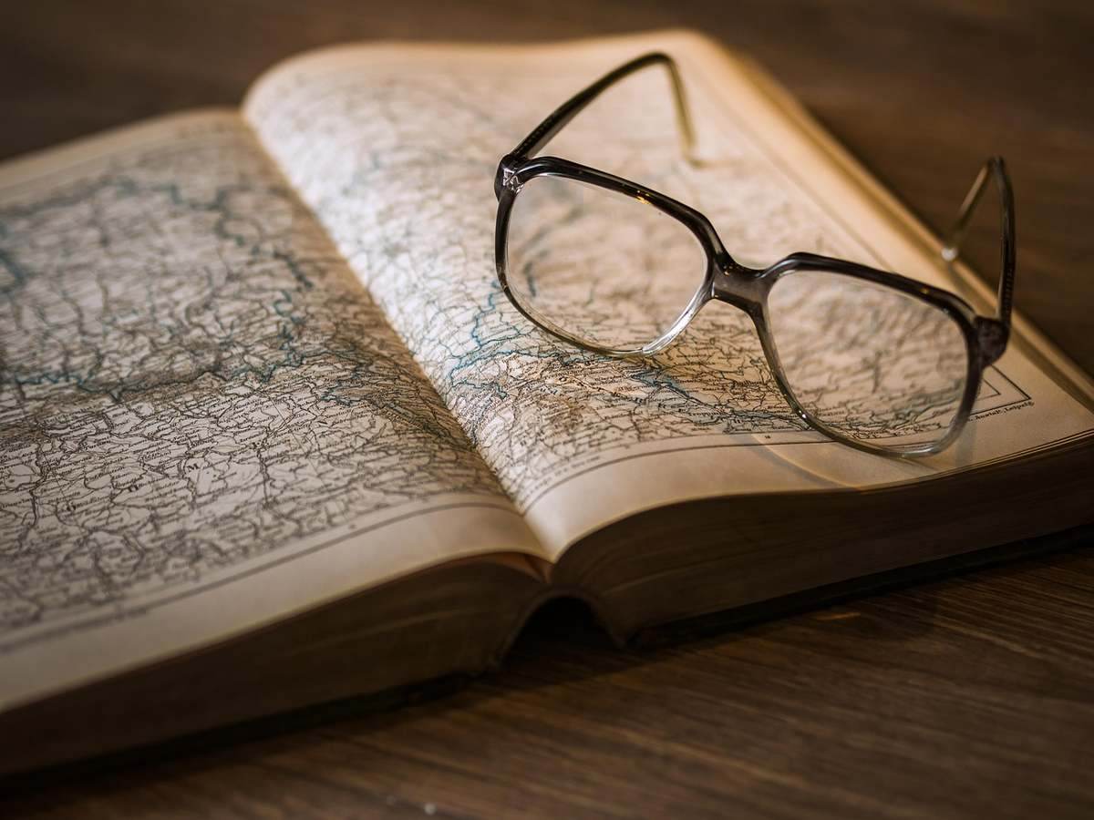 Lunettes posées sur un livre ouvert affichant une carte Lunettes posées sur un livre ouvert affichant une carte